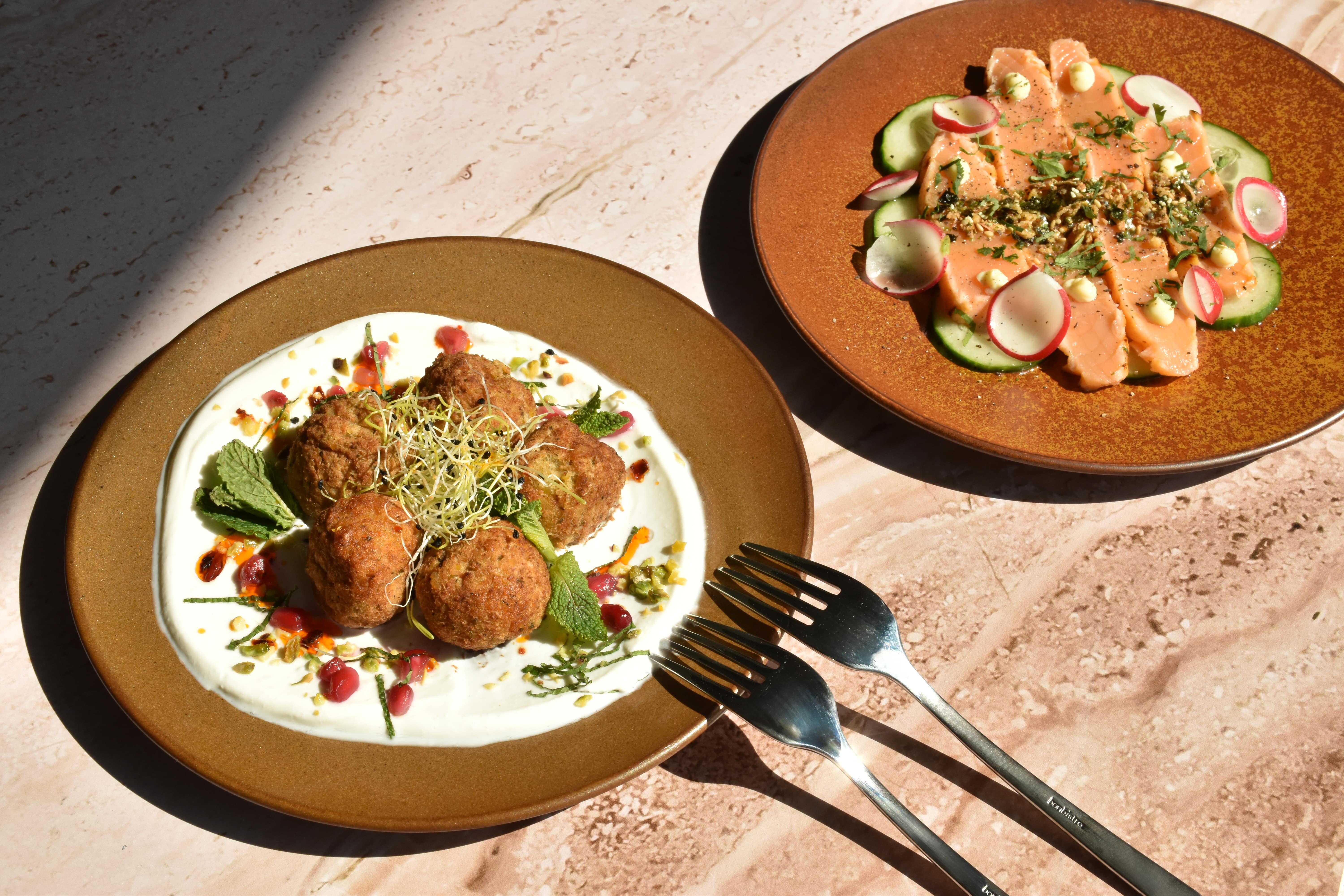 Summer presentation of salmon tataki and falafel with yogurt dip on rustic Ovio dinnerware, ideal for catering.